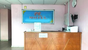 A reception desk with a sign that reads "PR MOTEL" and a sign indicating check-out time. - Capital O 91275 Pr Motel (Changlun)
