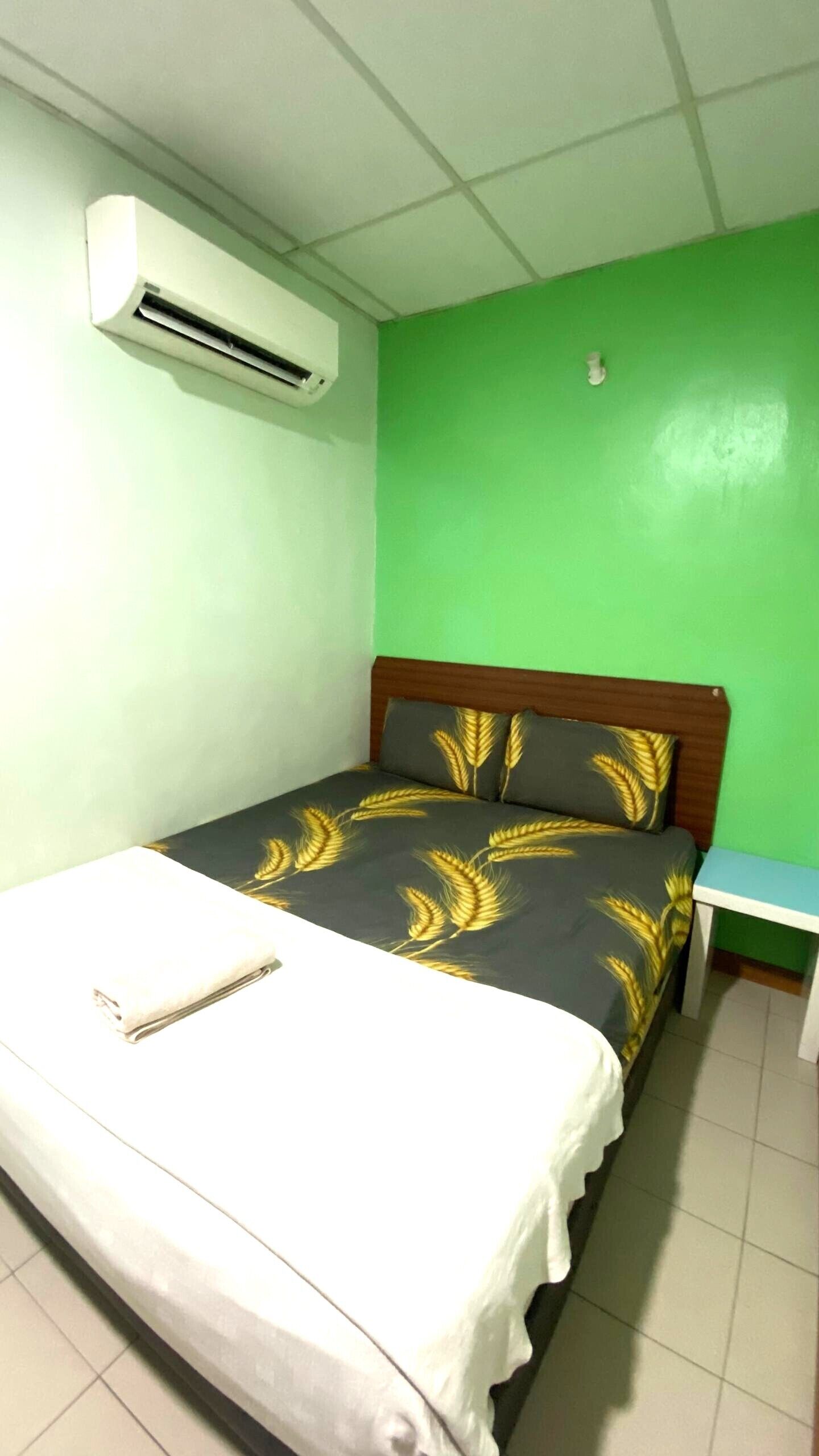 Una habitación con una cama, una mesita de noche y una pared verde.