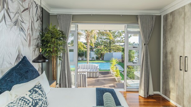 A bedroom with a large bed, a view of a pool, and a sliding glass door leading to an outdoor area.