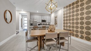 A modern kitchen with white cabinets, stainless steel appliances, and a wooden dining table with six chairs. - Modern Condo near Disney with Resort & Waterpark Access - 7801SD (Kissimmee)