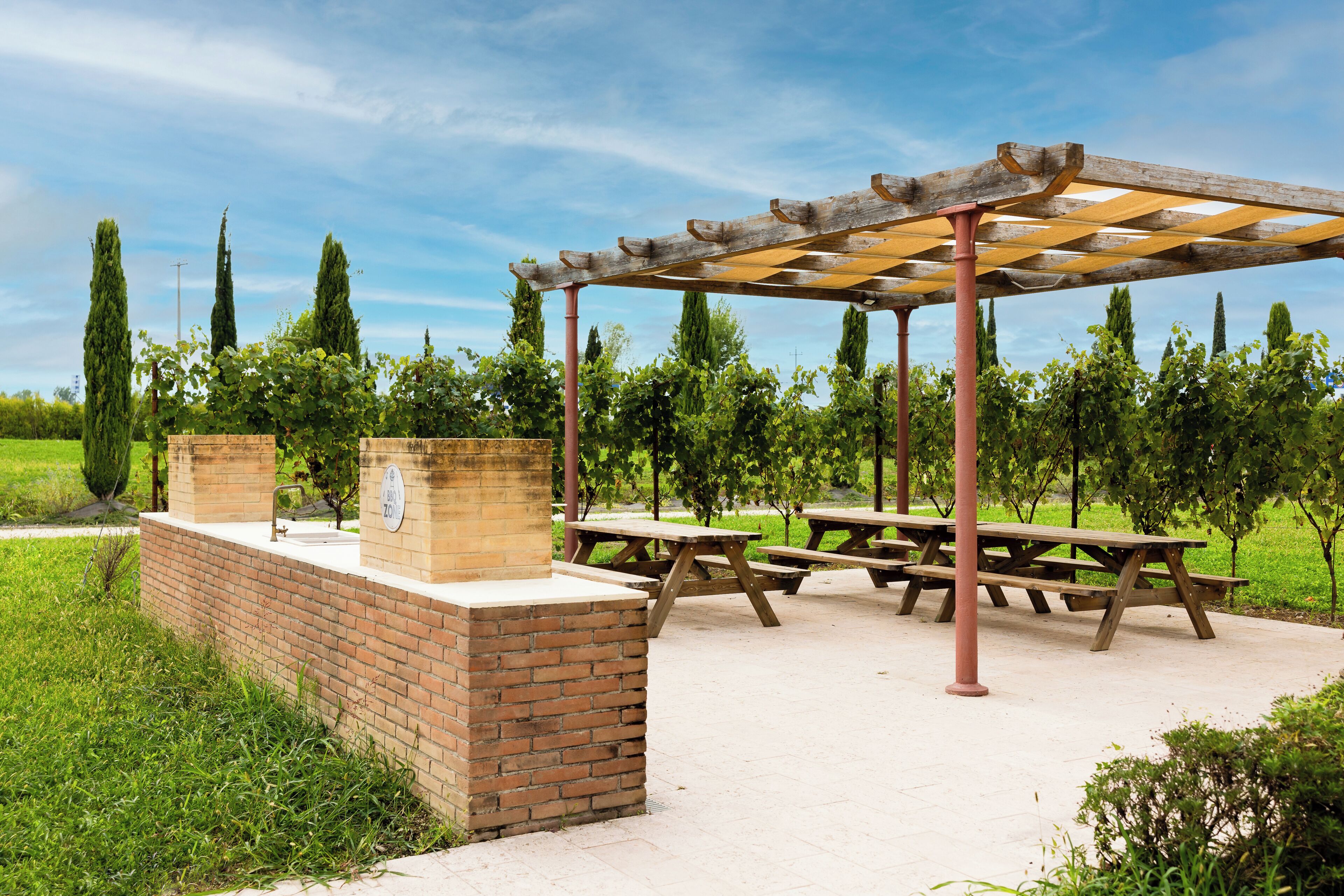Un espace pique-nique abrité, équipé de bancs et d’un jardinier en briques.