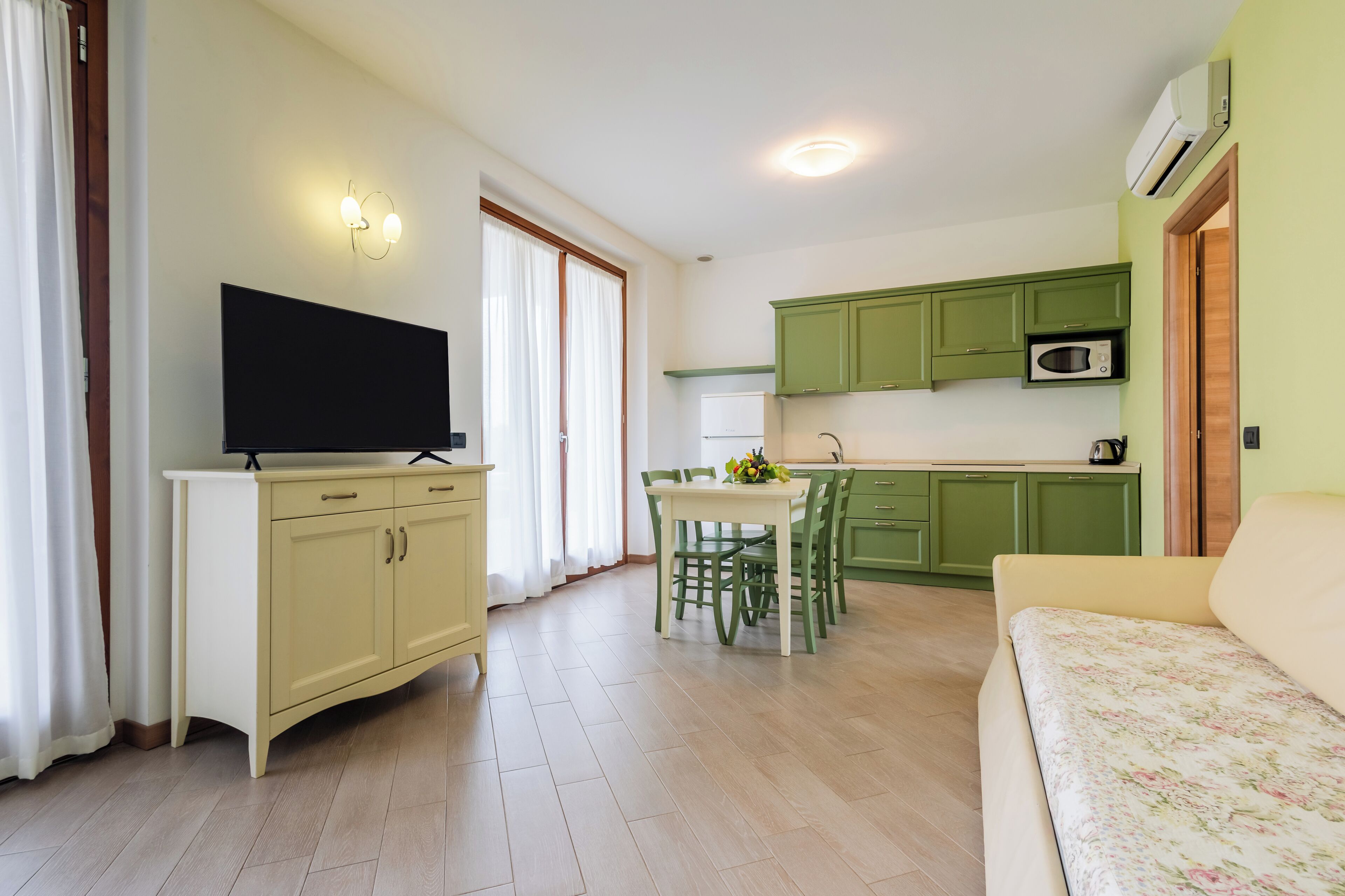 A compact living space with a dining area, kitchenette, and a television on a cabinet.