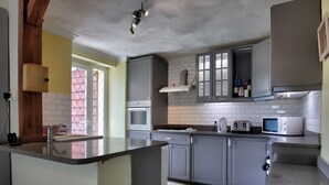 Una cocina con gabinetes grises, microondas, tostadora y pileta.