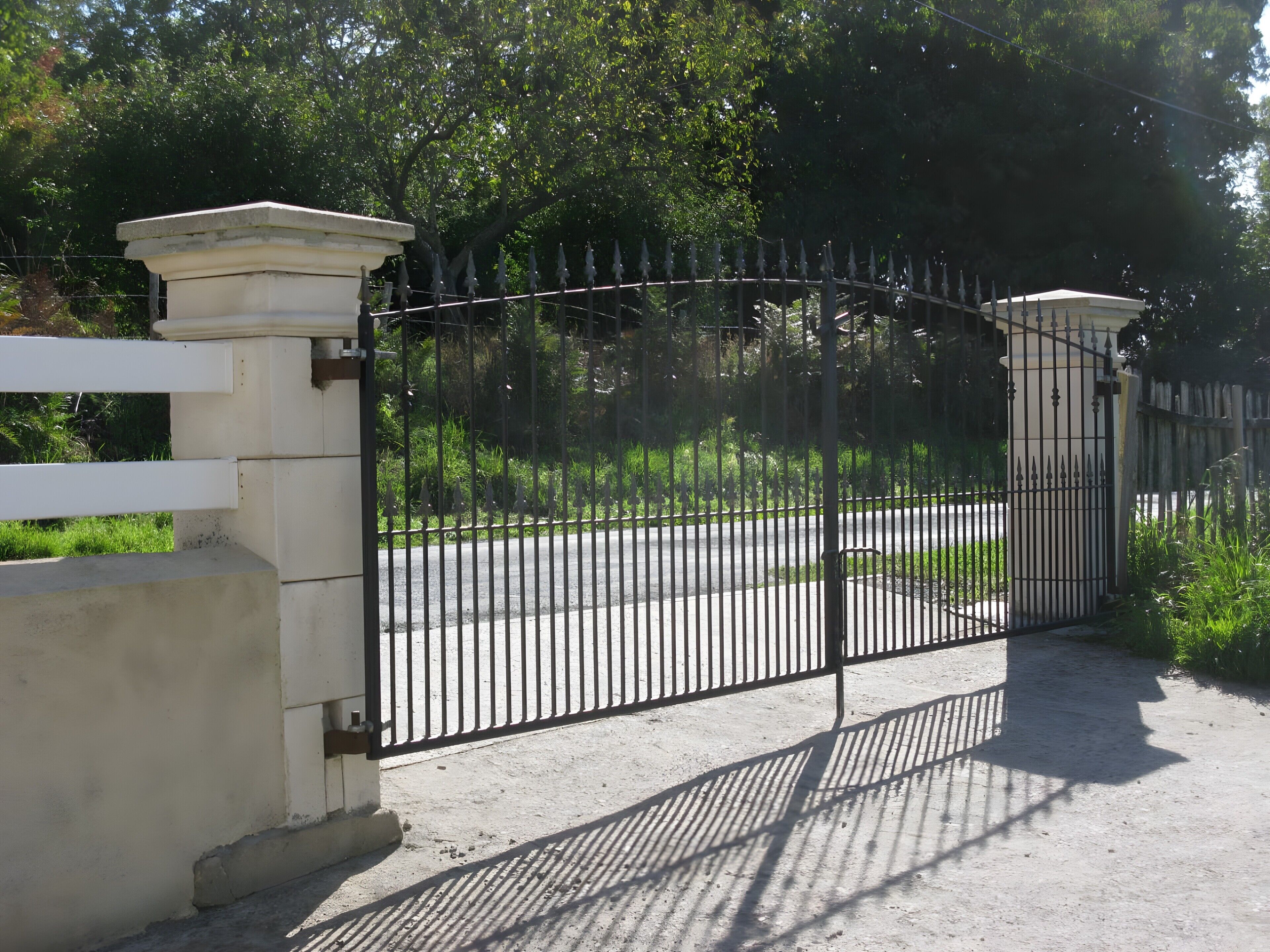 A gated entrance with a white fence and a black metal gate.