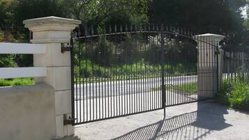 A gated entrance with a white fence and a black metal gate.