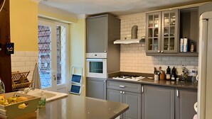 Una cocina moderna con armarios grises, horno empotrado y encimera con diversos utensilios de cocina.