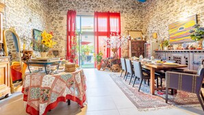 Una habitación de paredes de piedra con zona de comedor, un espejo grande y una cortina roja.