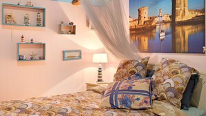 Un dormitorio con cama, dosel, un cuadro de paisaje urbano y estanterías con objetos decorativos.