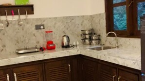 A kitchen with dark wooden cabinets, a marble countertop, a sink, and a window with a view of trees. - Sunsei Beach Negombo (Negombo)