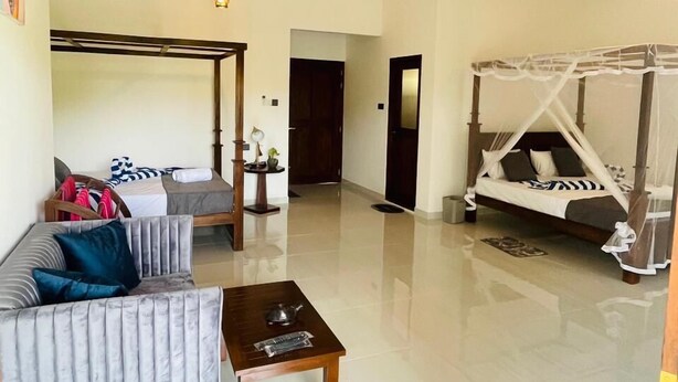 A spacious living area with a sofa, a coffee table, and a canopy bed. - Sunsei Beach Negombo (Negombo)