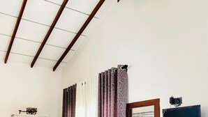 A hotel room with a wooden wardrobe, a console table with a vase, a mirror, and a TV mounted on the wall. - Sunsei Beach Negombo (Negombo)