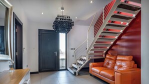 A modern interior with a staircase, leather sofa, and a unique chandelier. - Bellevue (Newtownabbey)