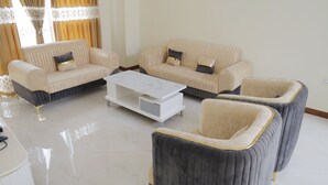 Een woonkamer met een zithoek, fauteuils en een salontafel.