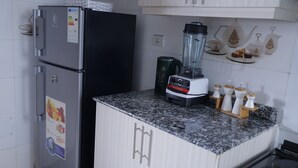Een keuken met een koelkast, een blender en een koffiezetapparaat op het aanrecht.