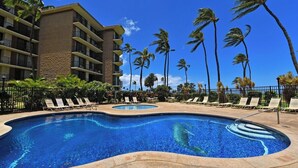 Ein Hotelpoolbereich mit zwei Pools, umgeben von Liegestühlen und Palmen.