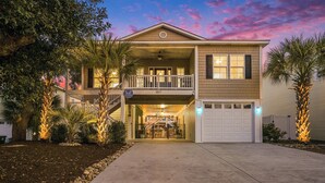 A two-story house with a balcony, a garage, and a driveway. - Brand NEW Heatable PRIVATE Pool| Mini-Golf |Hot Tub| Steps2Beach| Ground Floor Suite, Perfect for Families, Close to Everything in NMB! (North Myrtle Beach)
