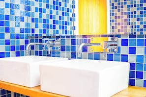 Ein Badezimmer mit zwei Waschbecken, Chromarmaturen und einem Holzschrank darüber.