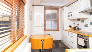 Una cocina moderna con armarios blancos, encimera de madera y horno integrado.