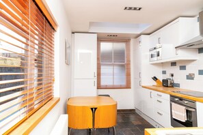 Eine moderne Küche mit weißen Schränken, einer Holz Arbeitsplatte und einem eingebauten Ofen.