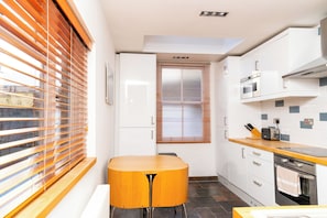 A modern kitchen with white cabinets, a wooden countertop, and a built-in oven. - Modern 1BDR Retreat | Near Queens Park & Seafront (Brighton and Hove)