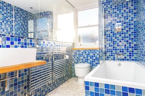 Un baño con una bañera blanca, un lavamanos blanco y una cabina de ducha de vidrio.