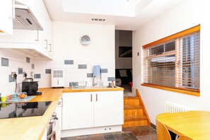 A modern kitchen with a built-in stove, a coffee machine, and a clock on the wall. - Modern 1BDR Retreat | Near Queens Park & Seafront (Brighton and Hove)