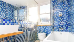 Un baño con una bañera blanca, un lavamanos blanco y una cabina de ducha de vidrio.