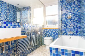 Ein Badezimmer mit einer weißen Badewanne, einem weißen Waschbecken und einer Dusche mit Glaswand.
