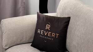A modern living room with a sofa, a decorative floor lamp, and a pillow with the text "REVERT RESIDENCE". - Revert Residence - Nespresso, Netflix and Premium Amenities Included (Brașov)
