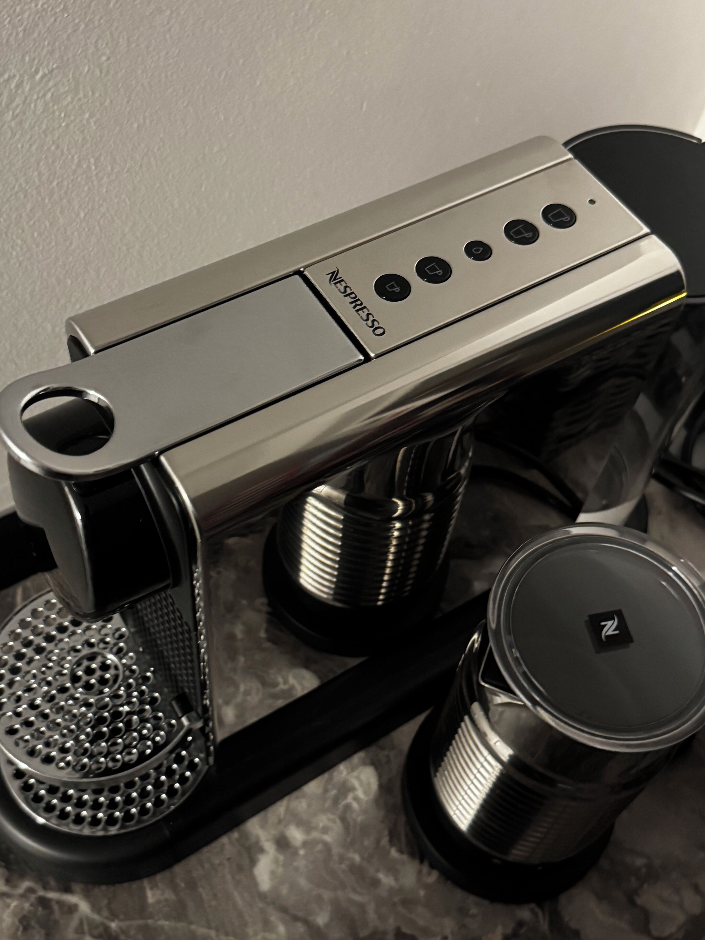 A Nespresso coffee machine with a sleek design, a drip tray, and a water reservoir.