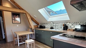 A modern kitchen with a skylight, wooden beams, and a view of mountains.