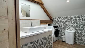 Une salle de bain moderne avec un plafond en bois, un lavabo, un lave-linge et un mur décoré d’un motif.