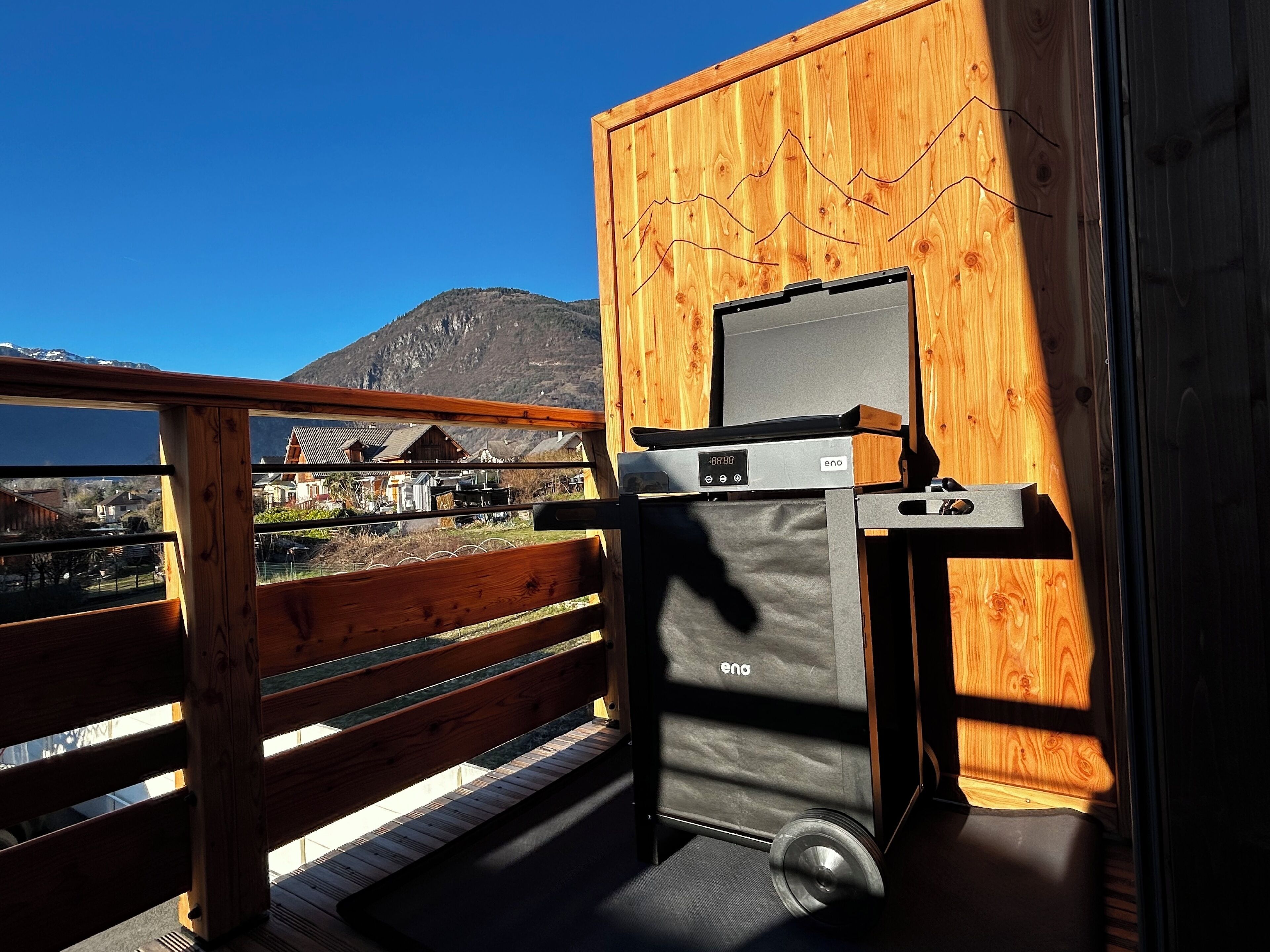 A compact room with a wooden exterior, a digital clock, and a small window overlooking a mountainous landscape.