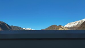A view from a window overlooking snow-capped mountains and a clear blue sky.