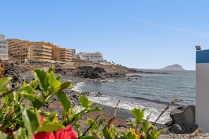 Un hotel costero con varios pisos, una costa rocosa y una vista despejada del mar.