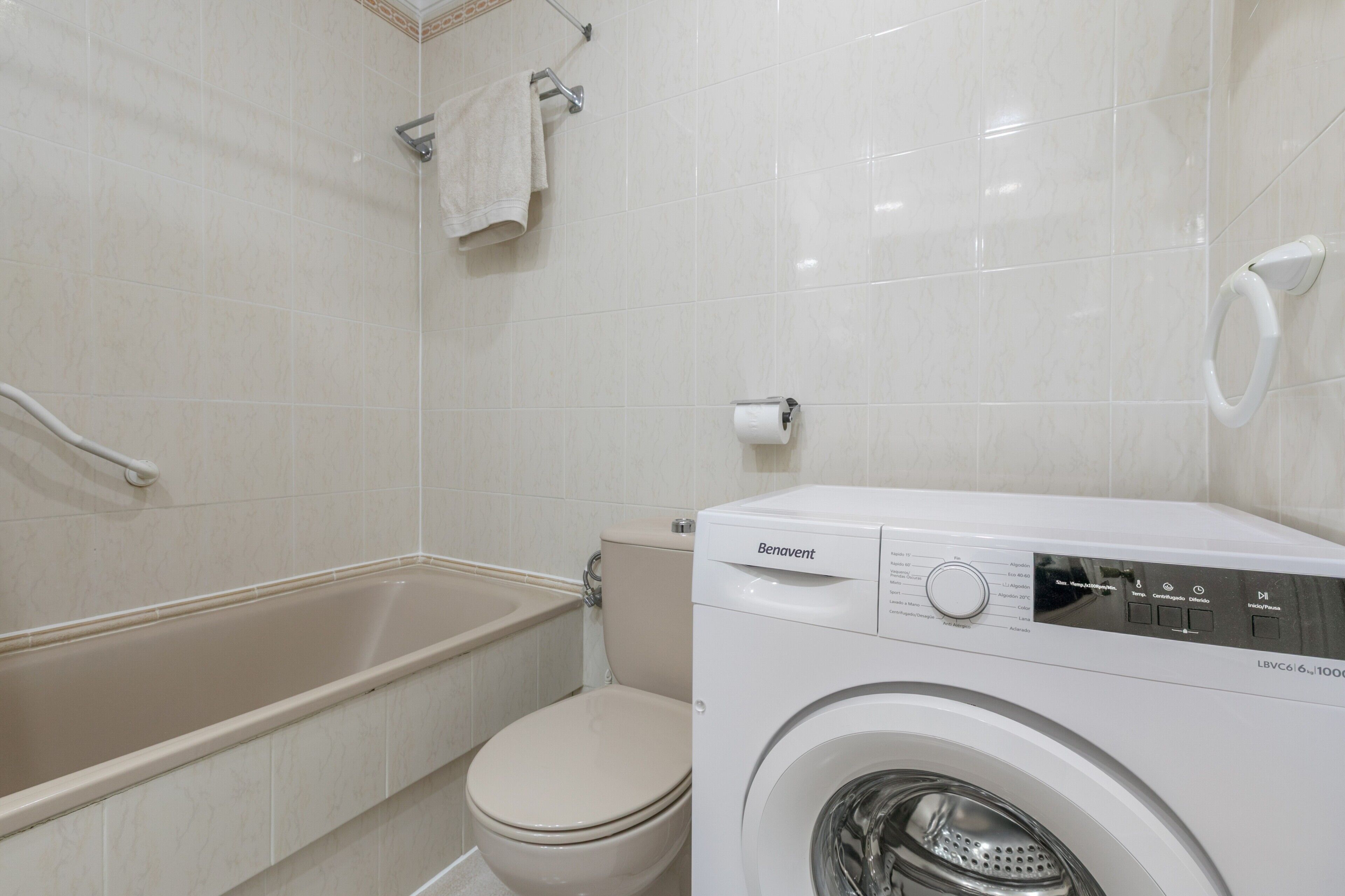 Un baño con bañera, inodoro y lavadora de carga frontal.