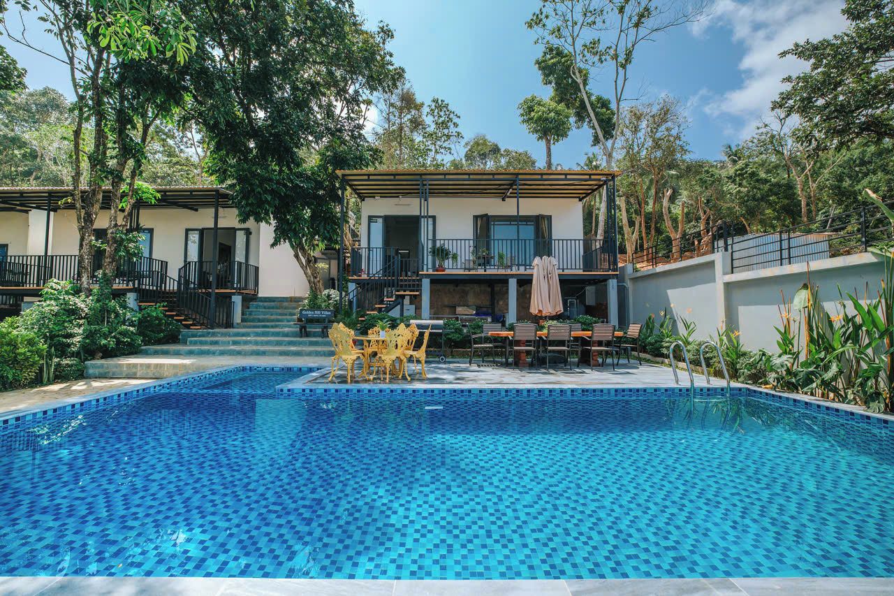 A pool area with a tiled floor, surrounded by a building with a balcony and outdoor seating.