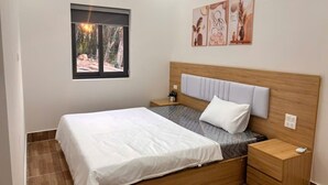 Een slaapkamer met een bed, nachtkastjes, een raam en wanddecoratie.