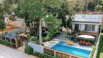 Una propiedad residencial con piscina, paneles solares y un patio cubierto.