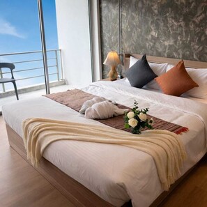 A neatly made bed with a white comforter, a beige throw blanket, and a decorative vase with white flowers. - Global Hills Hotel (Patong)