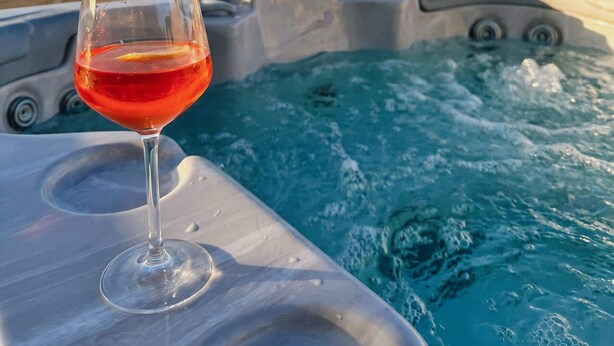 A hot tub with a glass of red drink on a balcony overlooking a cityscape. - Peaceful Home with Private Pool and Rooftop Jacuzzi (Ix-Xagħra)