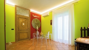 Un comedor con una puerta de madera, una mesa redonda con sillas y un adorno en la pared.
