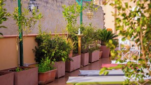 Un patio con plantas en macetas, mobiliario exterior y faroles colgantes.
