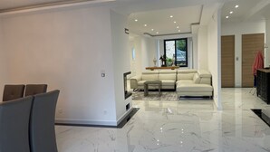 Un salon moderne avec un sol en marbre, un canapé d’angle beige et un ensemble de canapés gris.