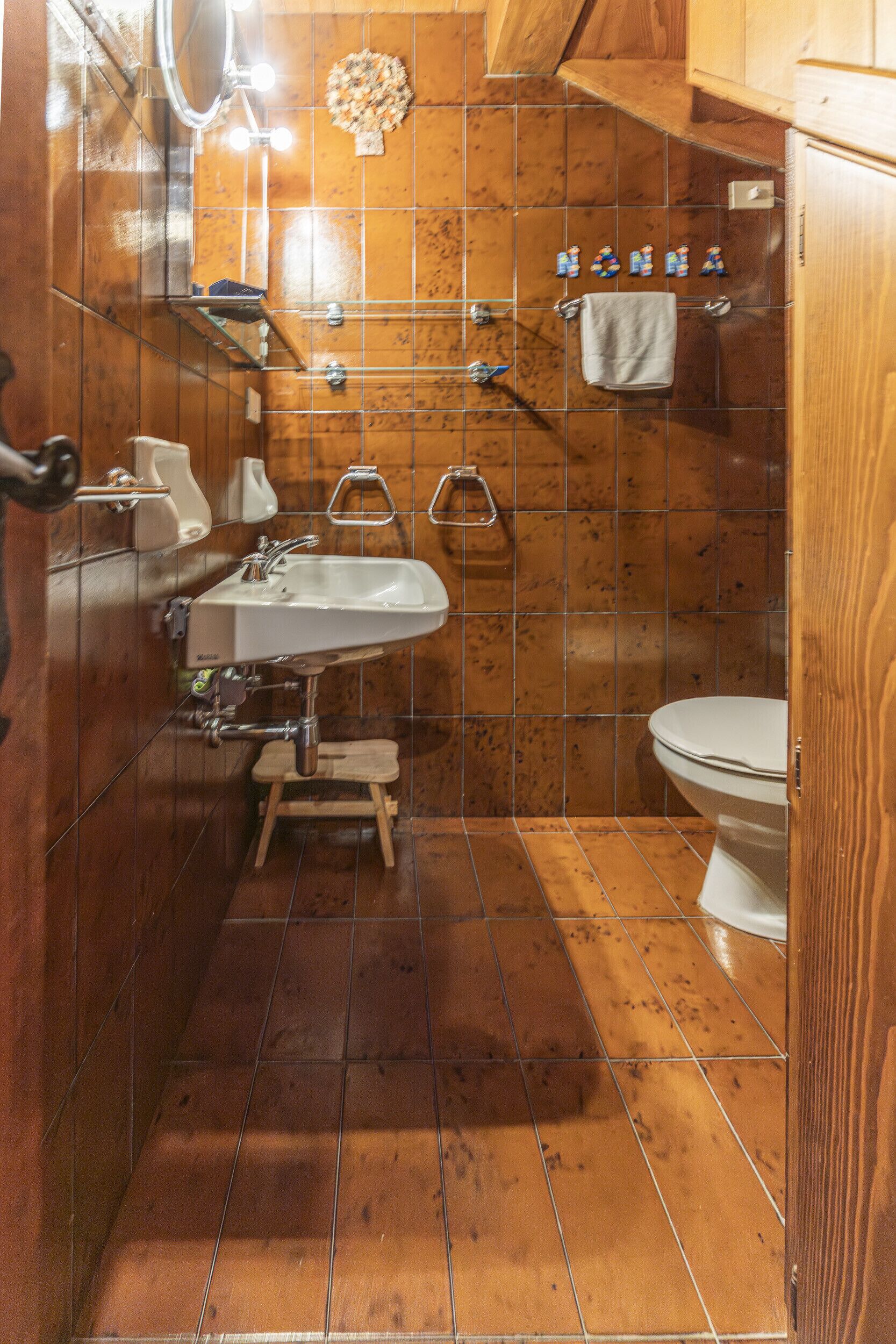 A bathroom with a wooden vanity, a sink, a mirror, and a toilet.