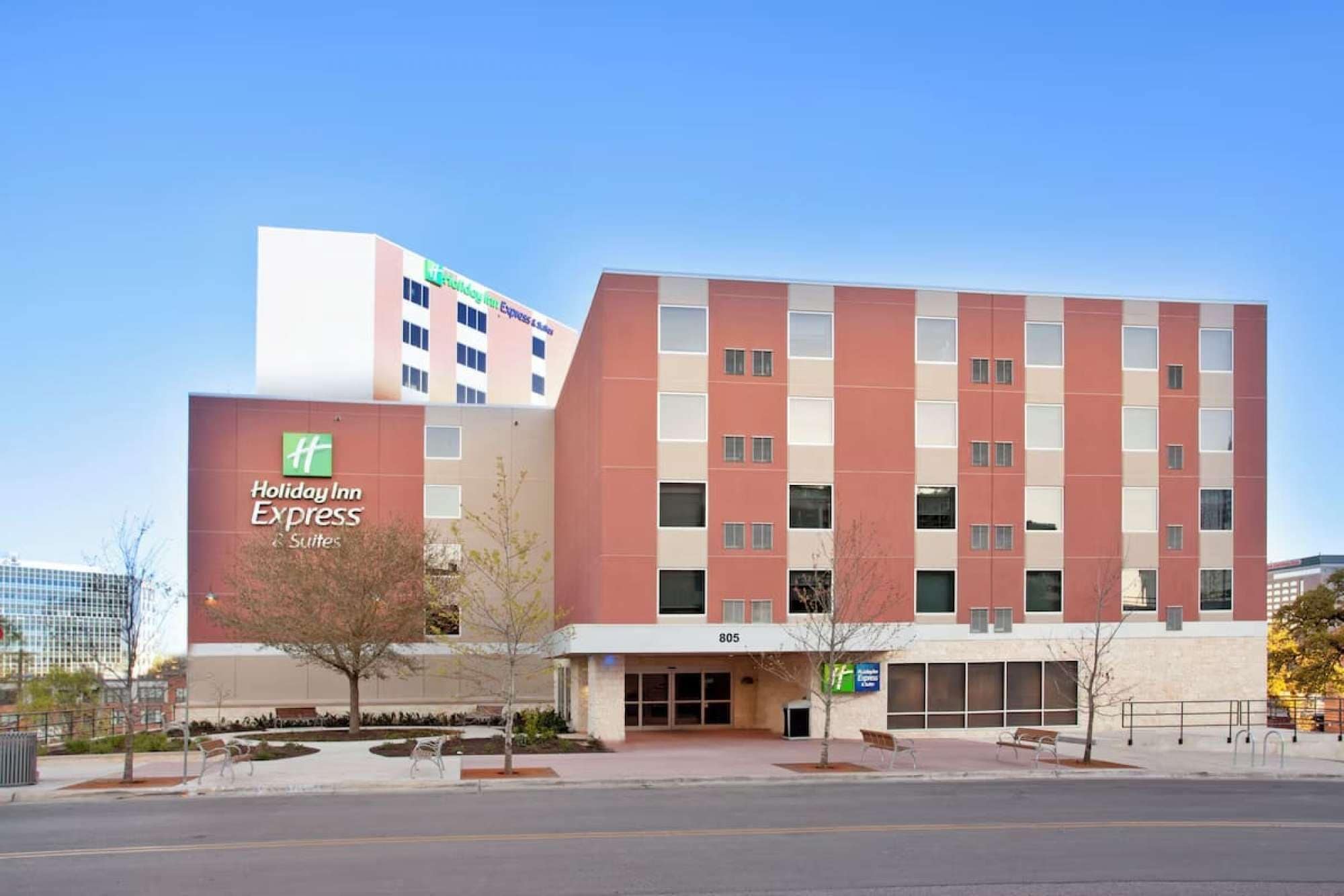 A Holiday Inn Express building with a modern design, featuring a mix of red and beige colors, large windows, and a flat roof.