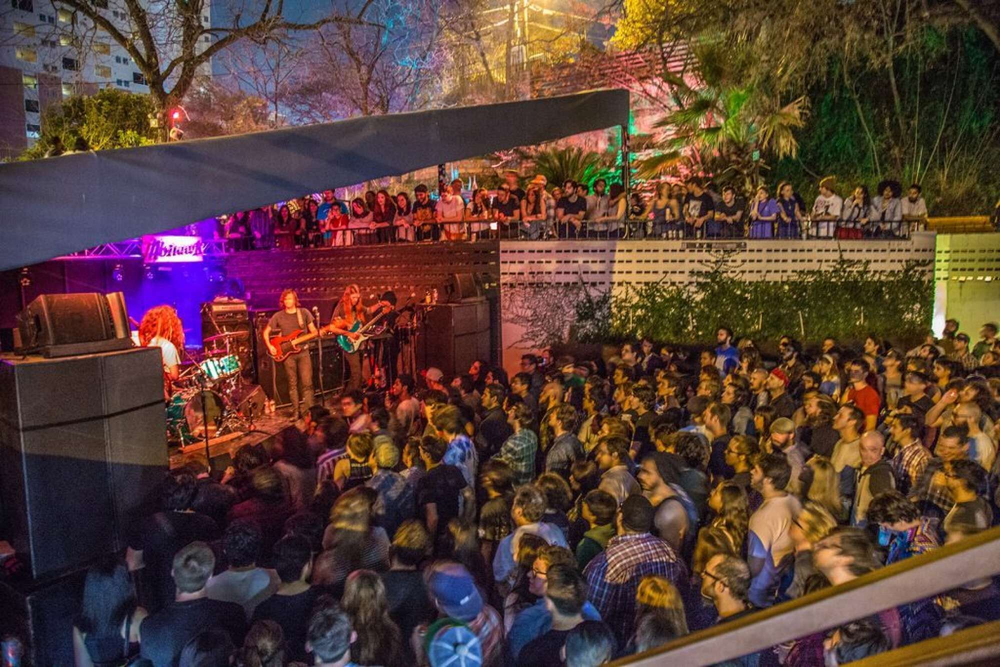A crowded outdoor concert with a stage and audience.