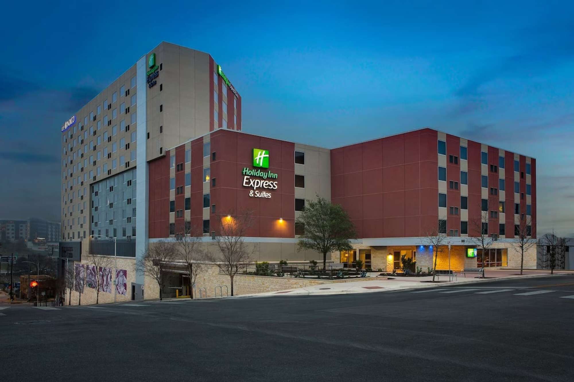 A Holiday Inn Express & Suites building with a modern design, featuring a prominent sign and a parking area in front.