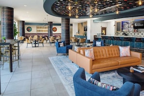 A hotel lobby with a bar area, seating arrangements, and a modern ceiling design. - Close to UT Austin + Rooftop Pool. Bar. Dining. (Austin)