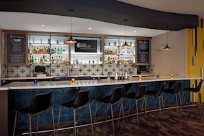 A bar area with a counter, bar stools, and shelves of bottles. - Close to UT Austin + Rooftop Pool. Bar. Dining. (Austin)